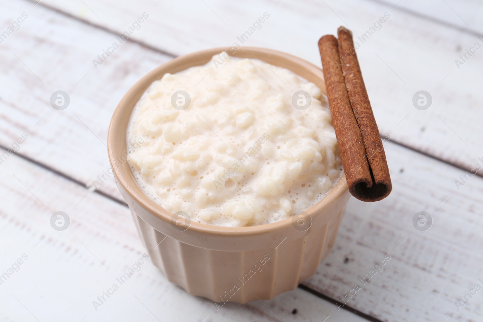 Photo of Tasty rice pudding with cinnamon on white wooden table, closeup