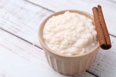 Photo of Tasty rice pudding with cinnamon on white wooden table, closeup. Space for text