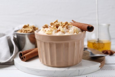 Photo of Tasty rice pudding with cinnamon served on white wooden table, closeup