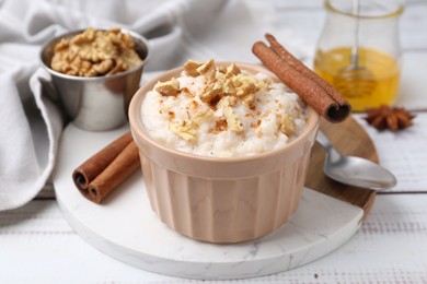 Photo of Tasty rice pudding with cinnamon served on white wooden table, closeup