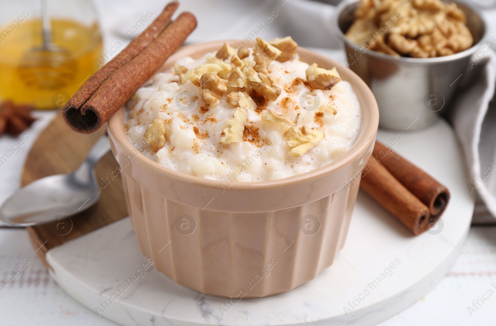 Photo of Tasty rice pudding with cinnamon served on white wooden table, closeup