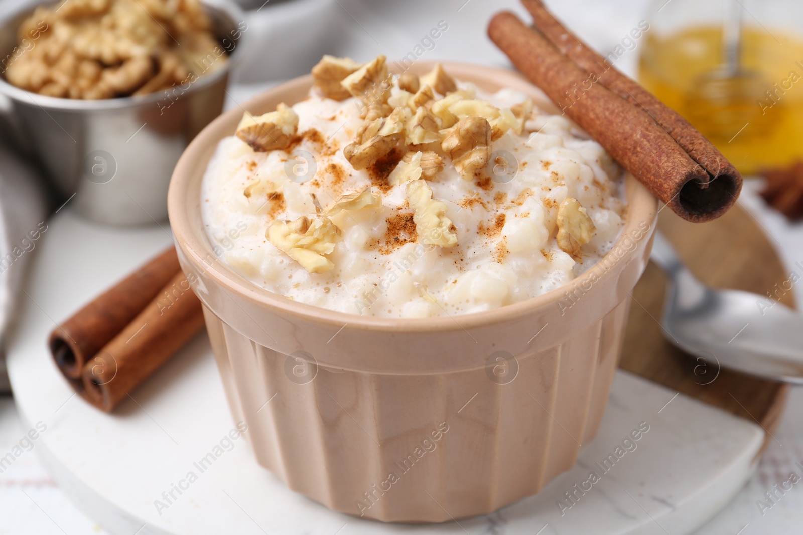 Photo of Tasty rice pudding with cinnamon served on white wooden table, closeup