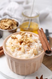 Photo of Tasty rice pudding with cinnamon served on white table, closeup