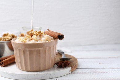 Photo of Tasty rice pudding with cinnamon served on white wooden table. Space for text