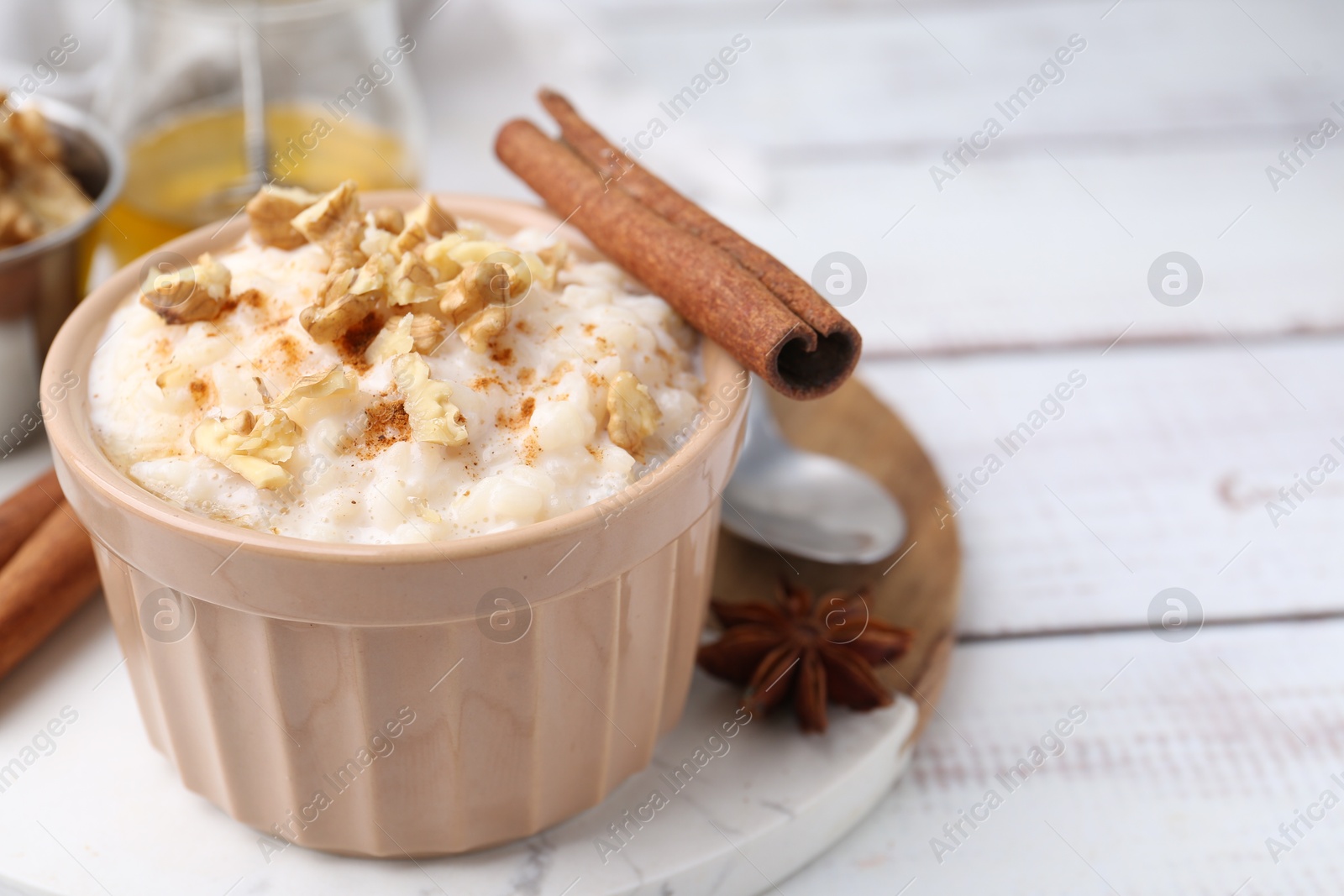 Photo of Tasty rice pudding with cinnamon served on white wooden table, closeup. Space for text