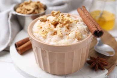 Photo of Tasty rice pudding with cinnamon served on white wooden table, closeup