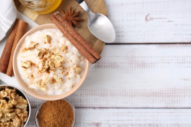 Photo of Tasty rice pudding with cinnamon served on white wooden table, flat lay. Space for text