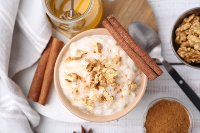 Photo of Tasty rice pudding with cinnamon served on white wooden table, flat lay