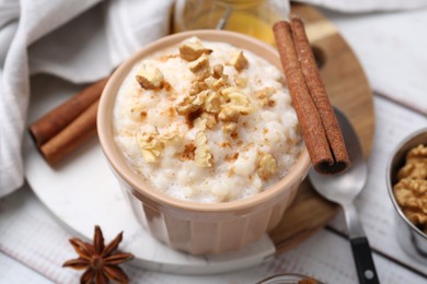 Photo of Tasty rice pudding with cinnamon served on white wooden table, closeup