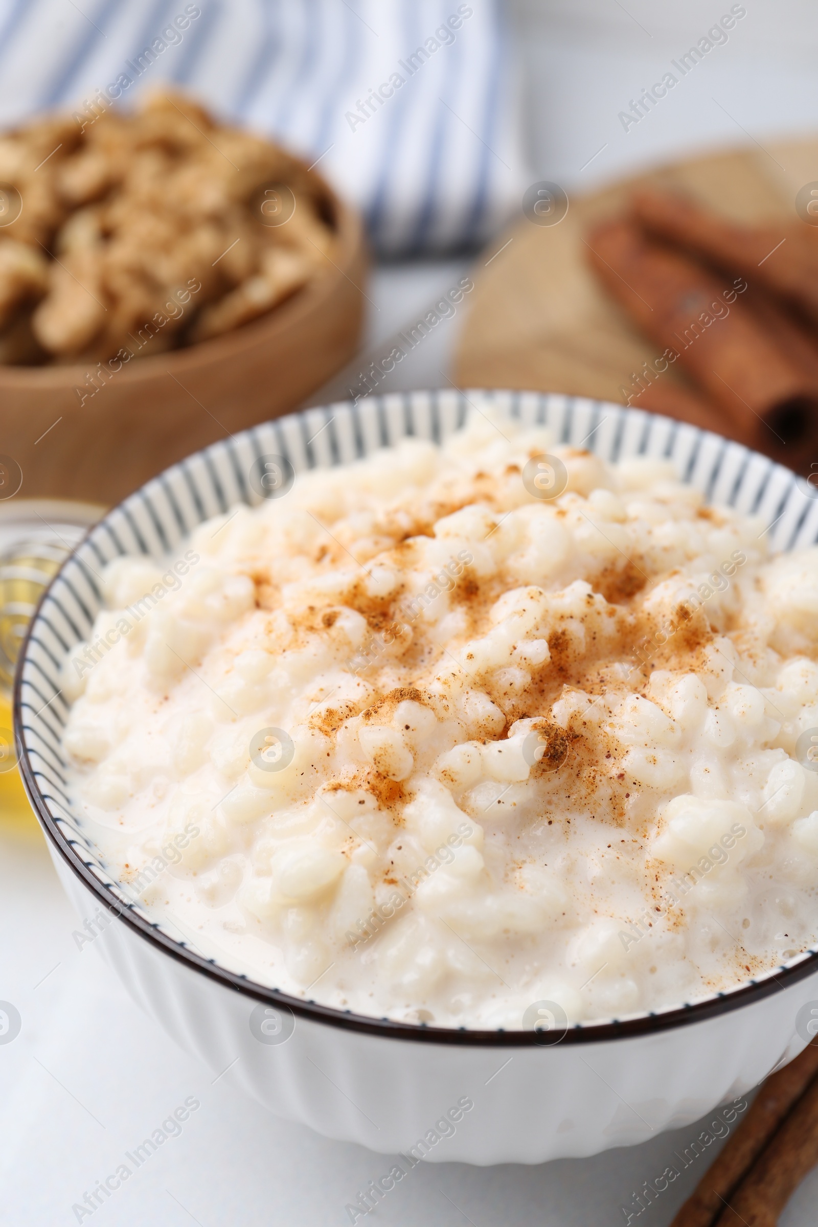 Photo of Tasty rice pudding with cinnamon served on white table, closeup