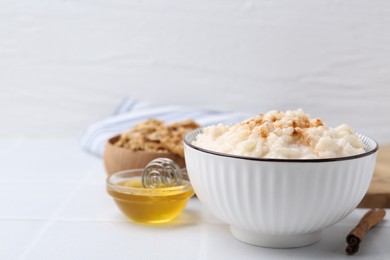 Photo of Tasty rice pudding with cinnamon served on white tiled table. Space for text