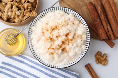 Photo of Tasty rice pudding with cinnamon served on white table, flat lay