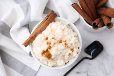 Photo of Tasty rice pudding with cinnamon served on white marble table, flat lay