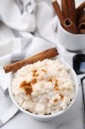 Photo of Tasty rice pudding with cinnamon served on white table, closeup