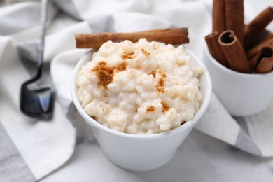 Photo of Tasty rice pudding with cinnamon served on white table, closeup