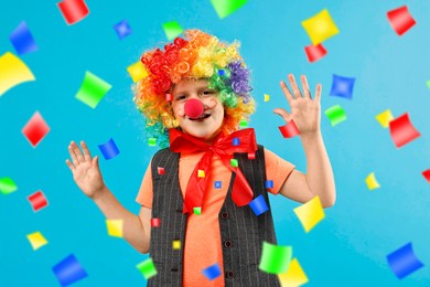 Image of Happy boy dressed like clown under falling confetti on light blue background. Party time