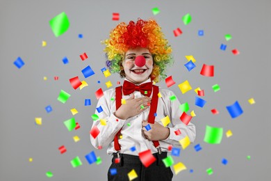 Image of Happy boy dressed like clown under falling confetti on grey background. Party time