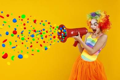 Image of Cute girl dressed like clown shouting in megaphone with confetti flying out of it on orange background. Party time