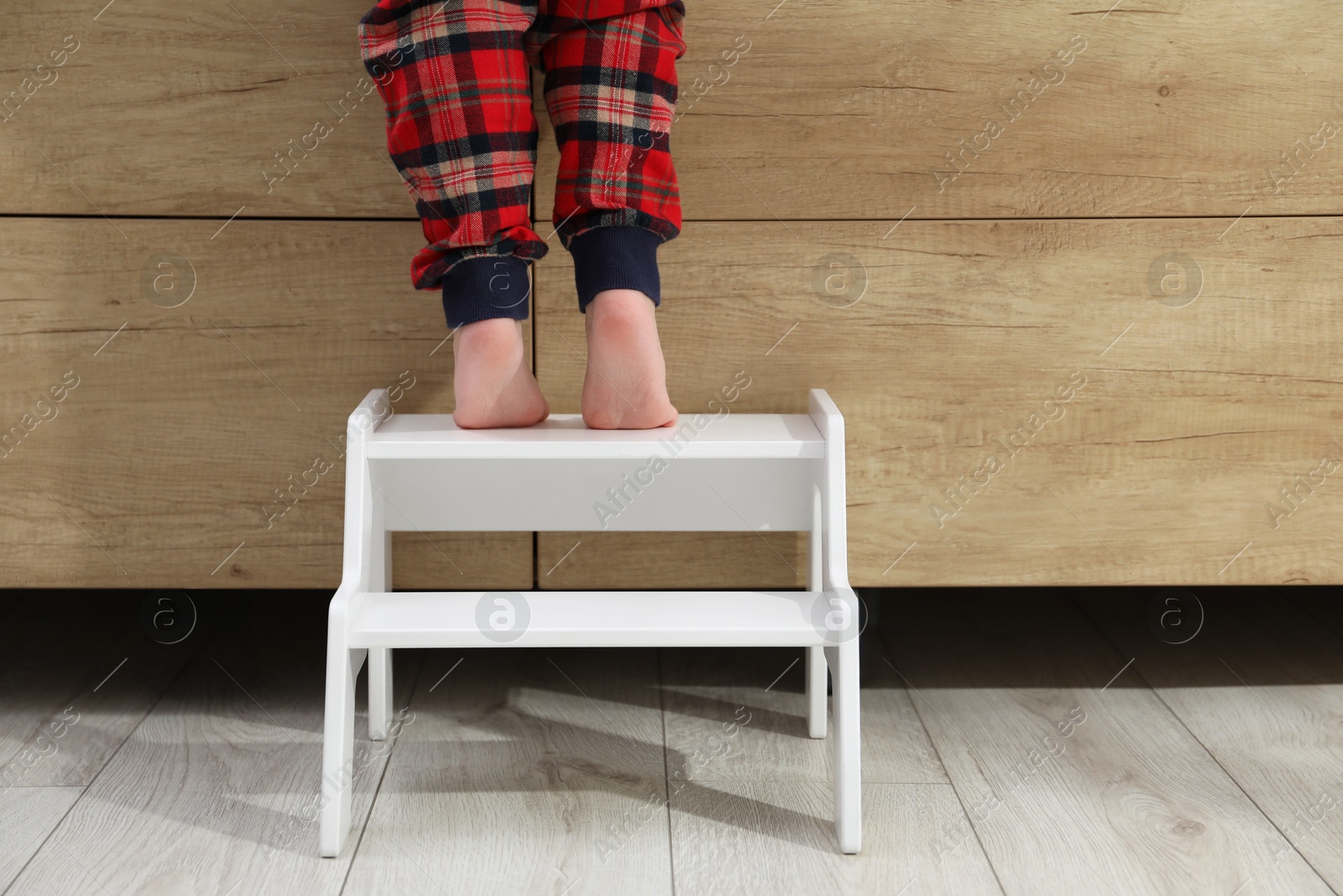 Photo of Little boy standing on step stool indoors, closeup