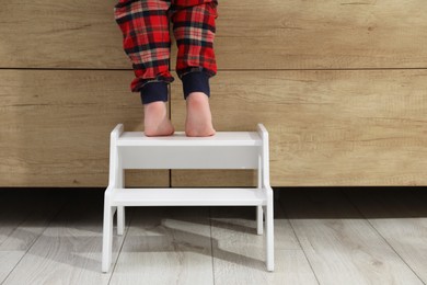 Little boy standing on step stool indoors, closeup