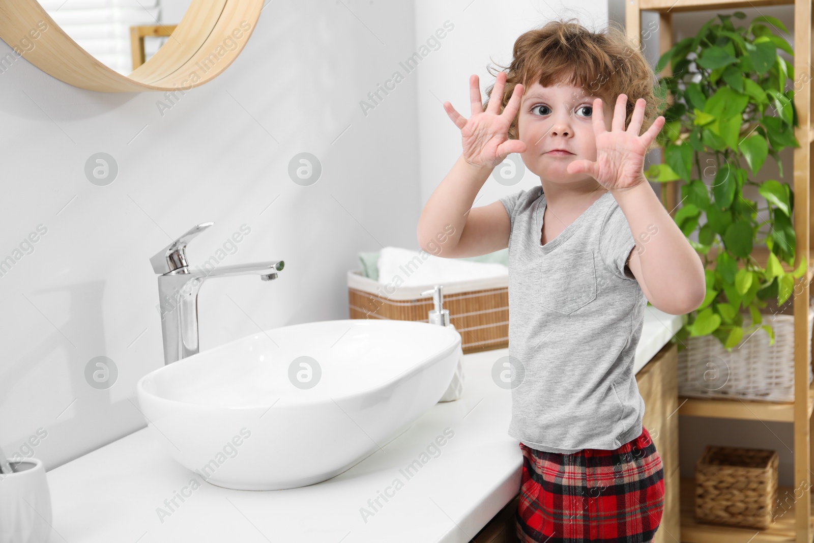 Photo of Portrait of little boy near bathroom vanity indoors