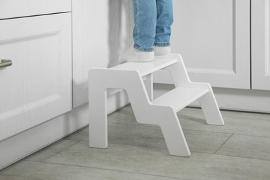 Little boy standing on step stool in kitchen, closeup