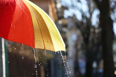 Photo of Open bright umbrella under pouring rain outdoors, closeup. Space for text