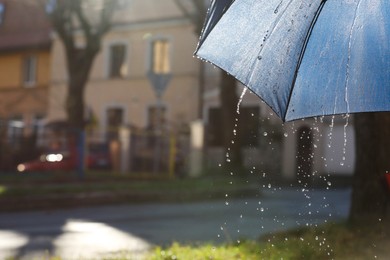 Photo of Open umbrella under pouring rain outdoors, closeup. Space for text