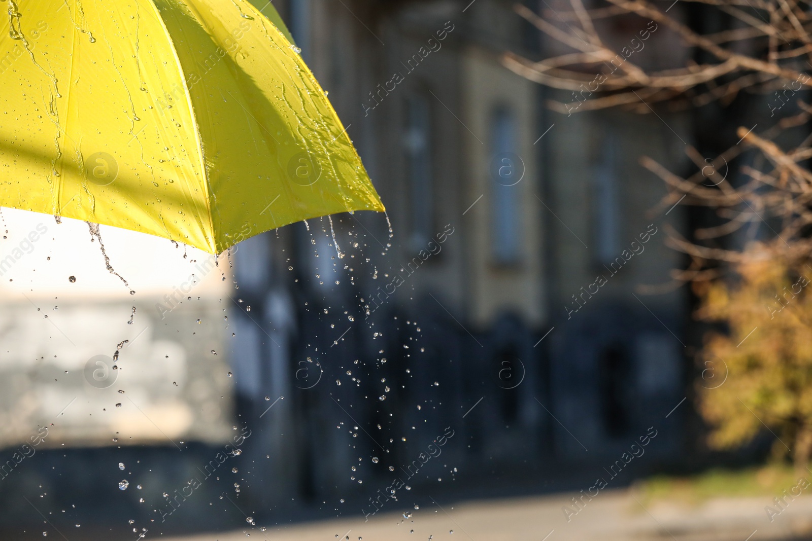 Photo of Open yellow umbrella under pouring rain outdoors, closeup. Space for text