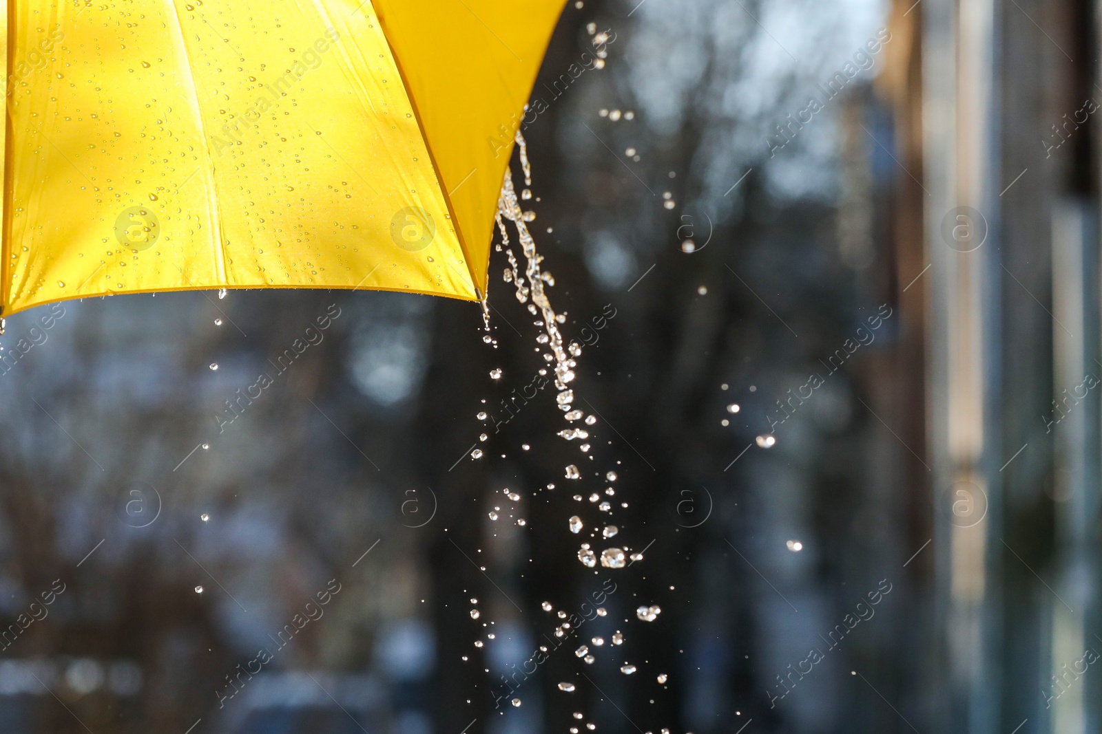 Photo of Open yellow umbrella under pouring rain outdoors, closeup