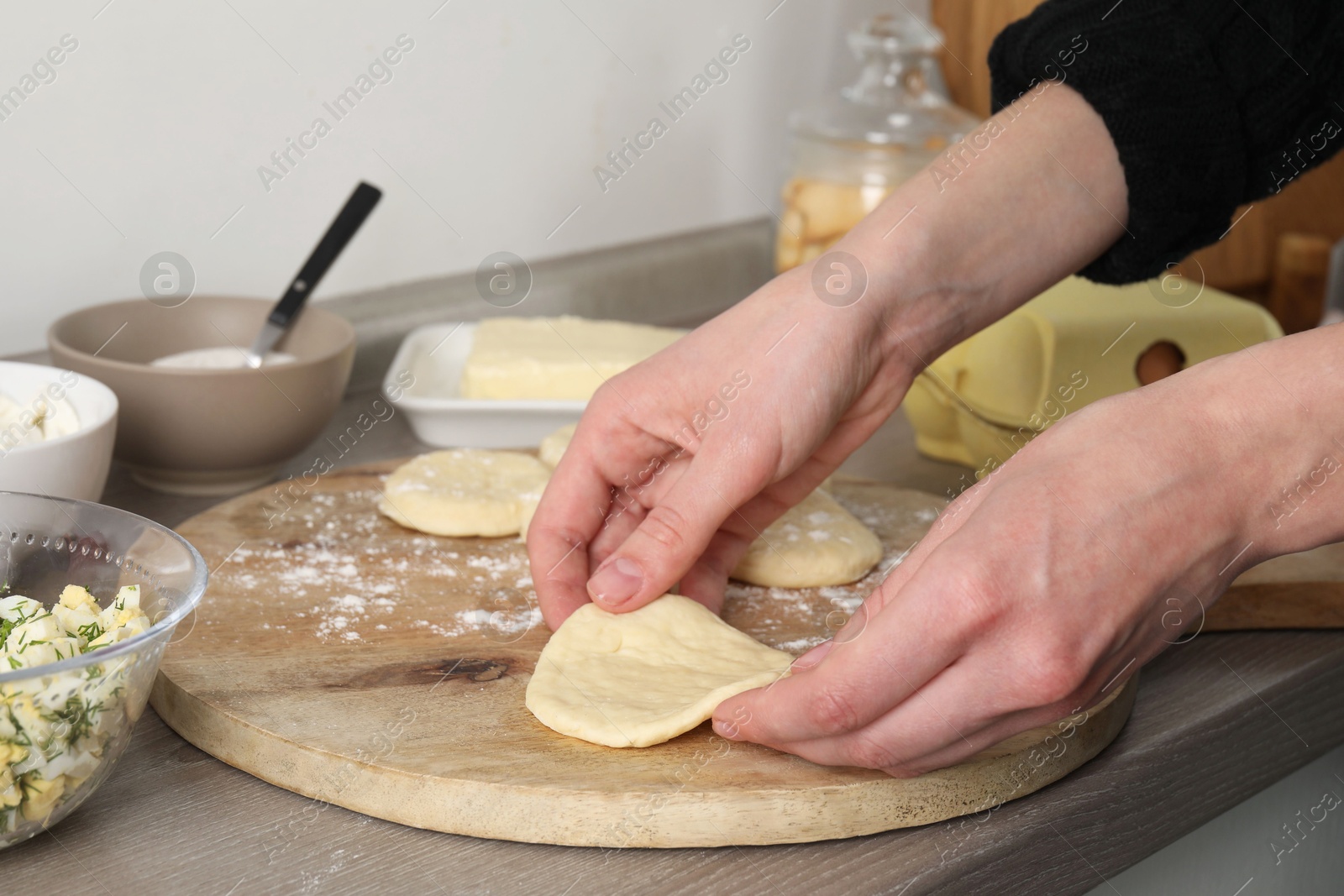 Photo of Woman making pirozhki (stuffed pastry pies) at countertop indoors, closeup