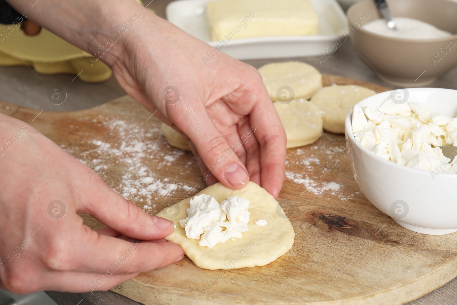 Photo of Woman making pirozhki (stuffed pastry pies) with cottage cheese at table, closeup