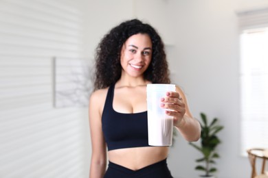 Photo of Beautiful woman with protein shake at home, selective focus