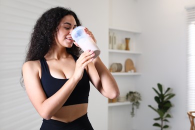 Beautiful woman drinking protein shake at home