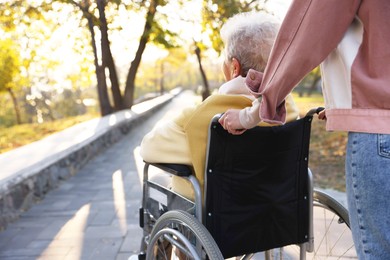 Photo of Caregiver with elderly woman in wheelchair at park, closeup