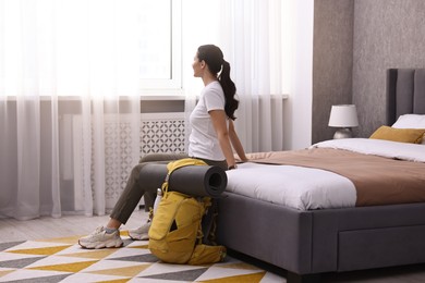 Traveller with backpack sitting on bed in hotel room