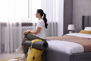 Traveller with backpack sitting on bed in hotel room