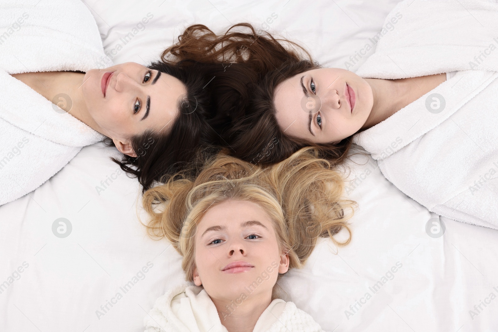 Photo of Spa day. Happy women lying on bed, above view