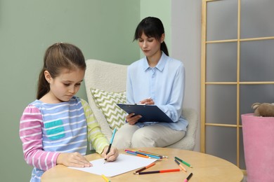 Photo of Little girl drawing during psychological evaluation in office