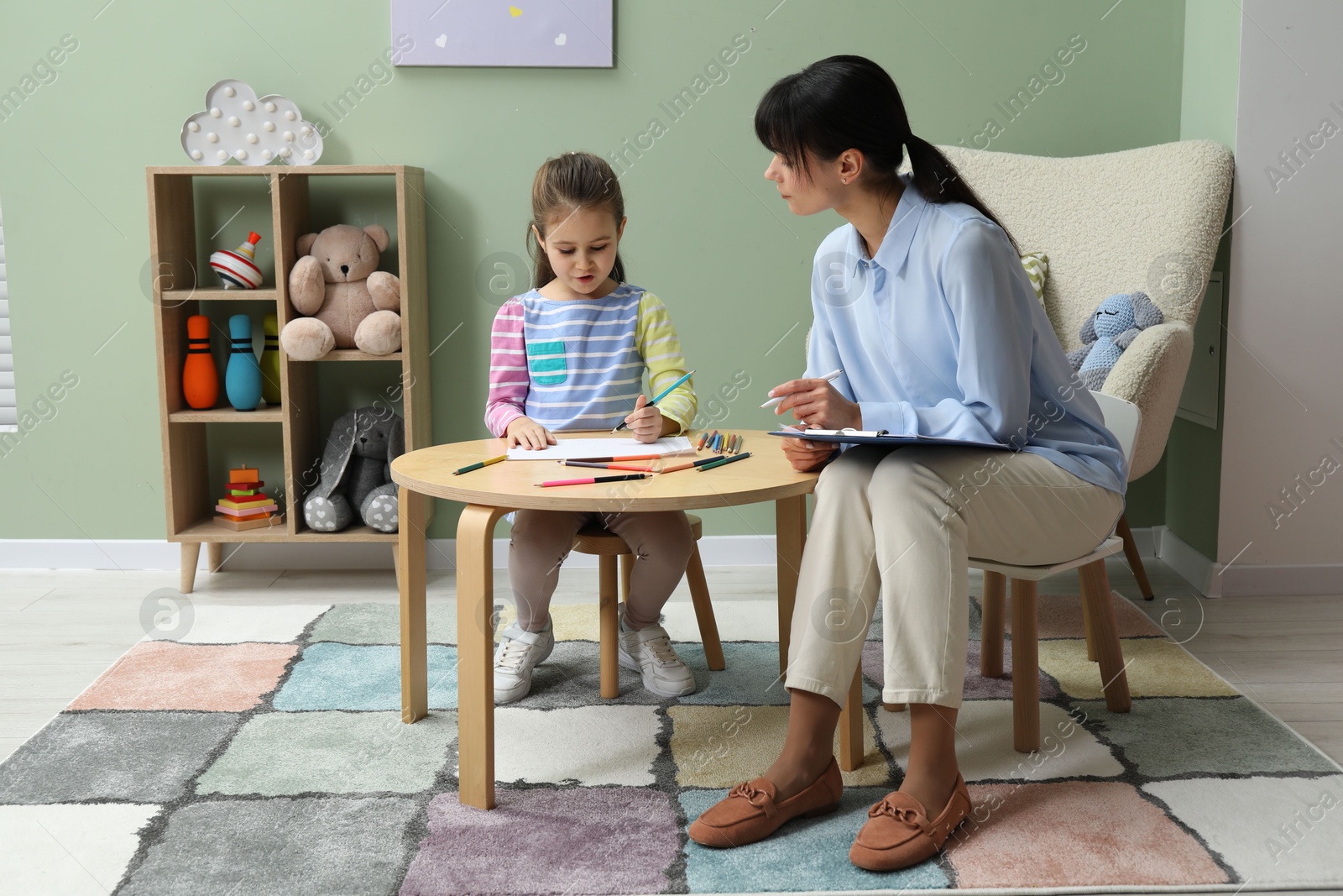 Photo of Little girl drawing during psychological evaluation in office