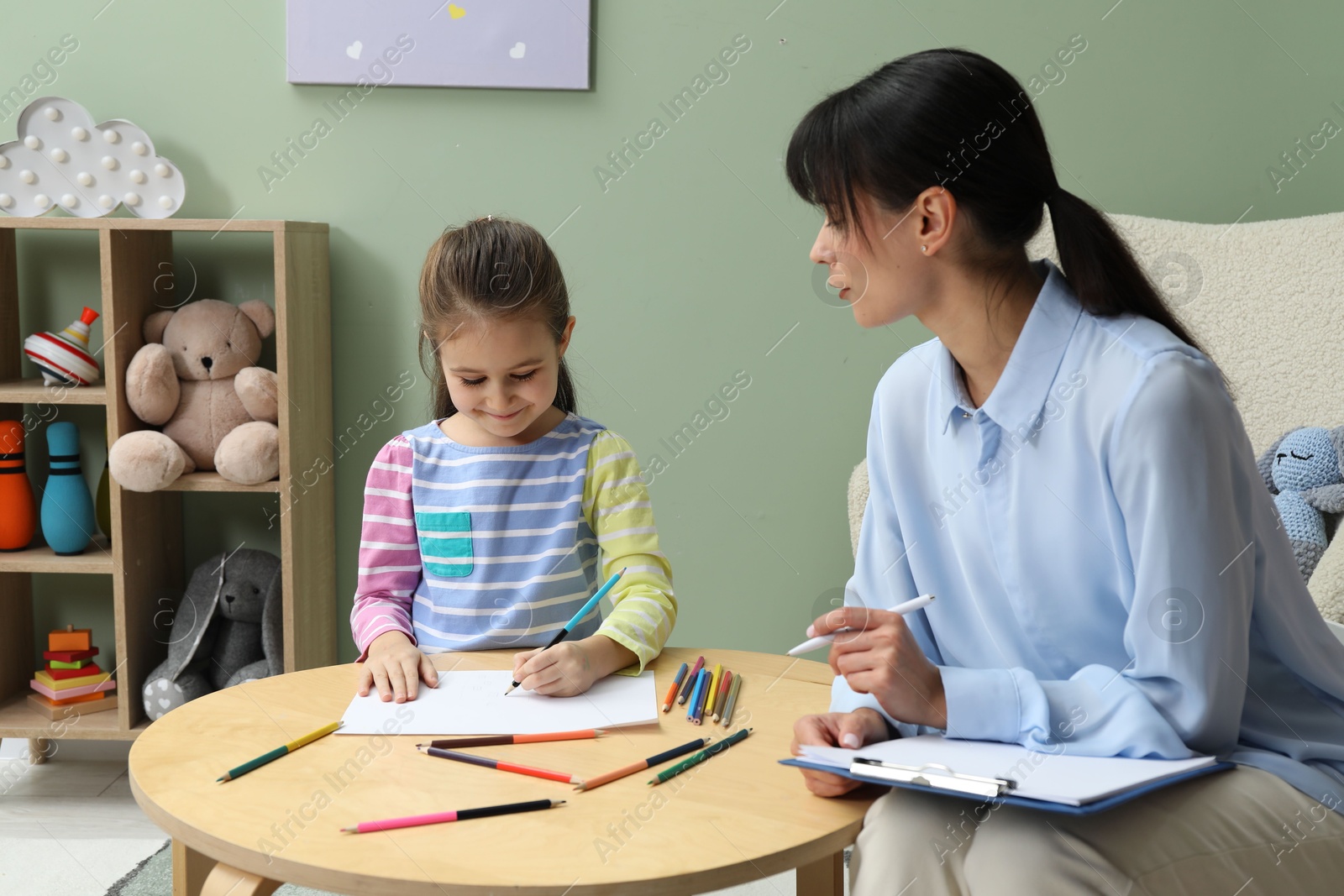 Photo of Little girl drawing during psychological evaluation in office