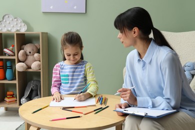 Little girl drawing during psychological evaluation in office