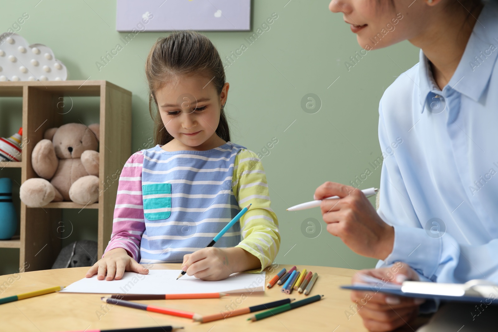 Photo of Little girl drawing during psychological evaluation in office