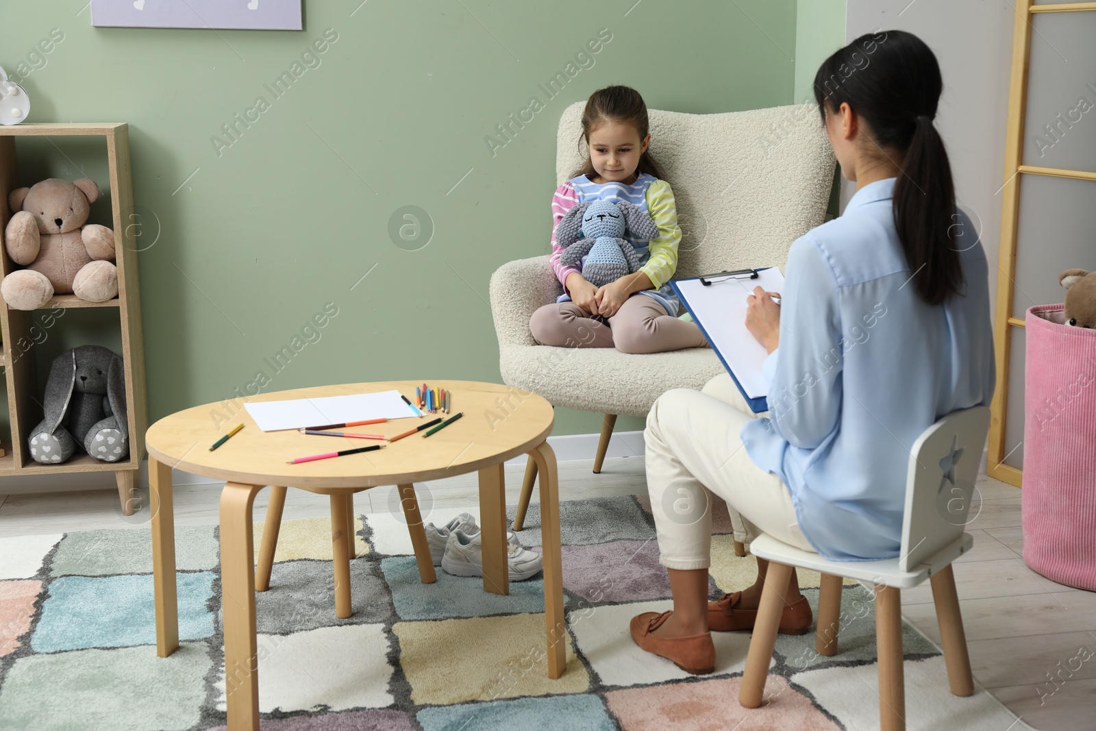 Photo of Psychologist having therapy session with little girl in office