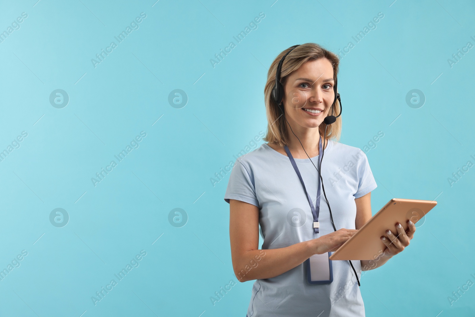 Photo of Technical support call center. Smiling operator with tablet on light blue background. Space for text