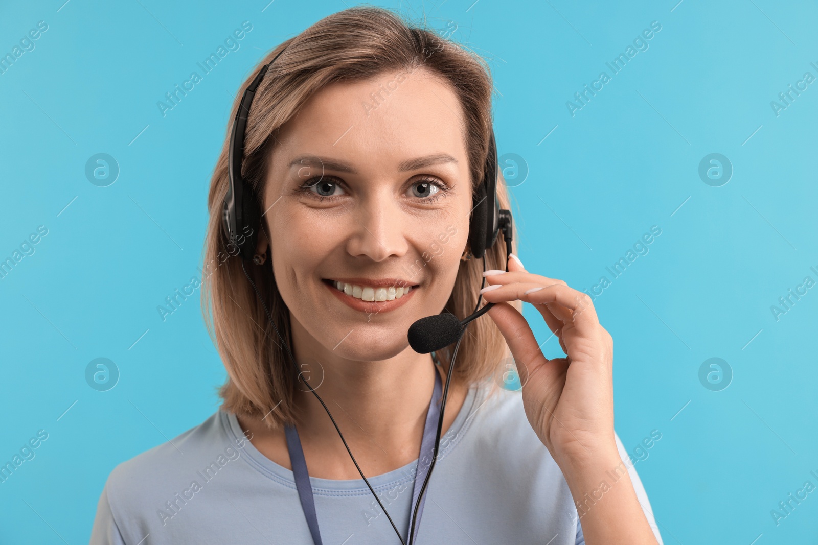 Photo of Technical support call center. Portrait of smiling operator on light blue background