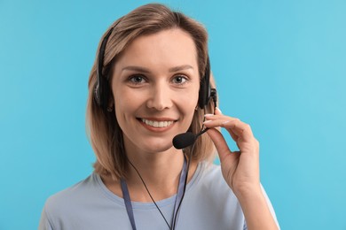 Photo of Technical support call center. Portrait of smiling operator on light blue background