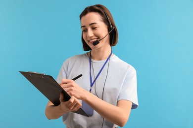 Technical support call center. Smiling operator with clipboard on light blue background