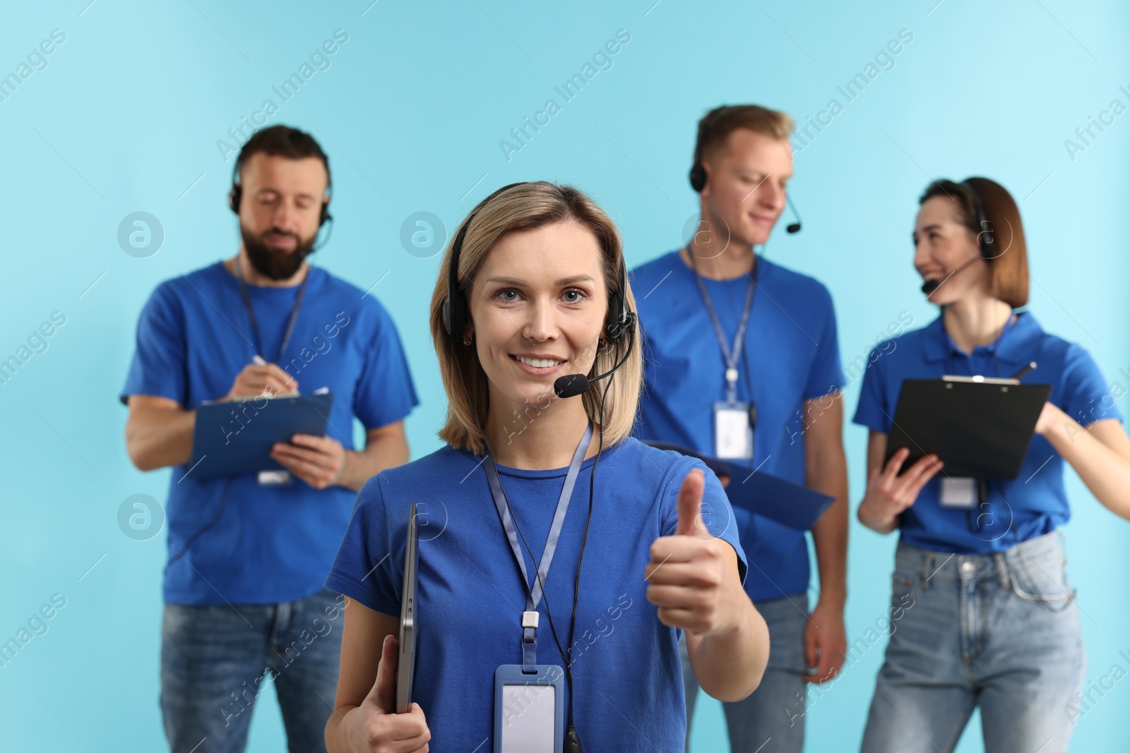 Photo of Technical support call center. Team of friendly operators on light blue background