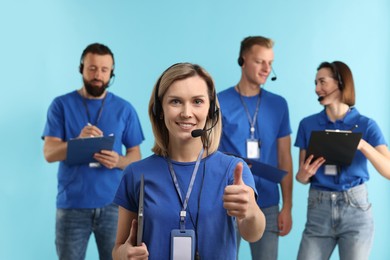 Photo of Technical support call center. Team of friendly operators on light blue background